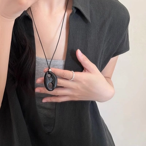 Close-up of a minimalist black resin oval pendant necklace with a stylish silver bead accent