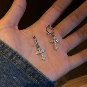 Macro detail of silver cross earrings with shimmering cubic zirconia on palm
