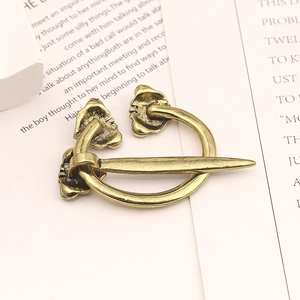 Macro shot of a vintage gold Viking brooch with animal heads resting on an open book