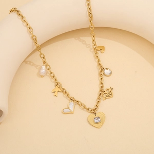 Detail of a gold charm bracelet featuring colorful heart-shaped and pearl-like pendants