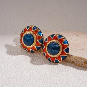 Macro shot of vintage round earrings with blue stones and red enamel sunburst patterns