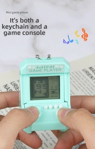 Close-up of a hand holding a mint green mini retro arcade game console keychain
