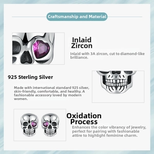 Detailed macro view of 925 sterling silver skull stud earrings with heart-shaped red zircon