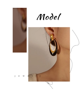 Close-up of vintage oval enamel earrings in gold and black finish on a model