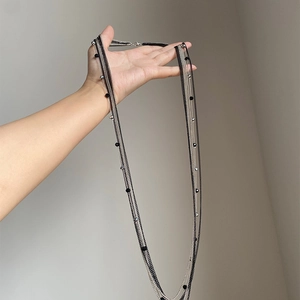 Dettaglio macro della collana a più strati in metallo argento e nero con perle