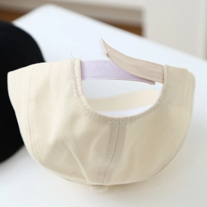 Detail view of the adjustable velcro strap on a beige cotton baby baseball cap
