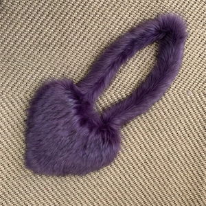 Detail of purple faux fur heart-shaped handbag with plush texture on woven background