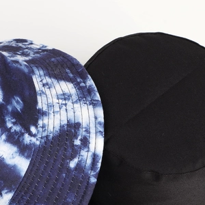 Detailed close-up of blue tie-dye and black bucket hat fabrics showing fine stitching