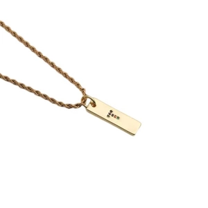 Detailed close-up of a golden twist chain necklace with a colorful zircon letter T pendant