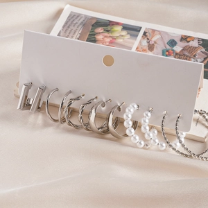 Detailed set of six pairs of minimalist silver-tone geometric earrings on a card display