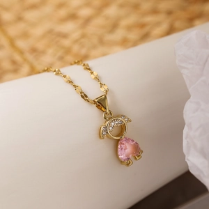 Dettaglio della collana dorata con ciondolo bambina e pietra di zircone a cuore rosa