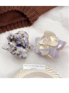 Detailed shot of acetate flower hair claws in marble purple and creamy shell finishes
