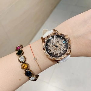 Close-up of women's watch with rotating flower dial and rose gold rhinestone bezel