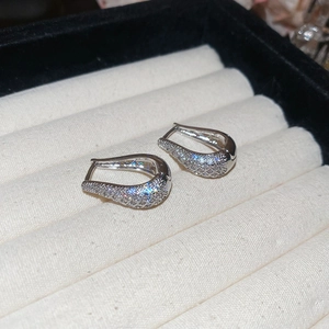 Vue détaillée des boucles d'oreilles argentées en U avec pavé de cristaux sur un plateau