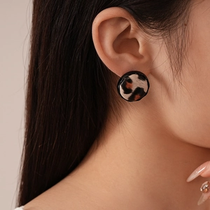 Close-up of leopard print round stud earrings featuring classic faux leather texture and retro design