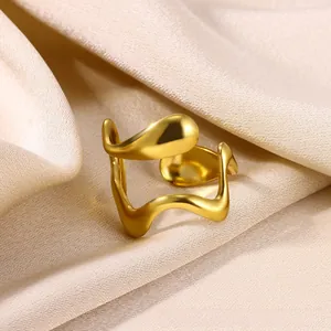 Macro shot of irregular wave-shaped gold ring with polished surface on champagne silk fabric