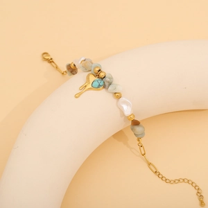 Detailed view of beaded bracelet with turquoise stones and a gold heart charm