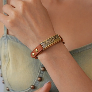 Detail of vintage leather bracelet with metal plate engraved with inspirational text