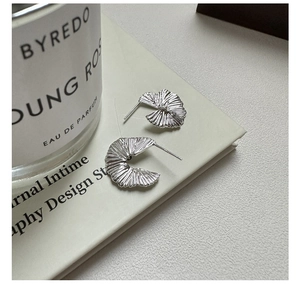 Detailed macro view of S925 sterling silver pleated fan earrings on a white display