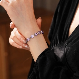 Elegant silver bracelet with circular purple zircons worn on wrist against velvet