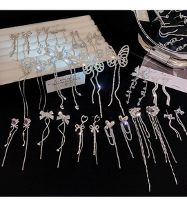 Macro shot of silver bow and heart tassel earrings with sparkling rhinestones details