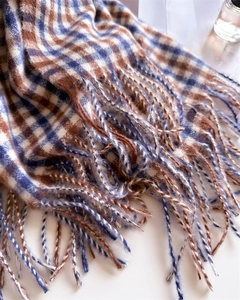 Close-up of blue and brown checkered scarf featuring soft fringed edges and wool texture