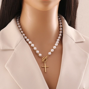 Collier de perles avec pendentif croix dorée et fermoir OT sur un mannequin femme