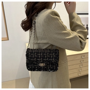 Lifestyle view of black tweed chain crossbody bag with golden hardware on a model