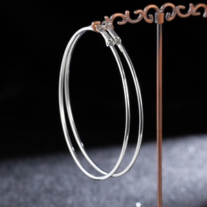 Close-up of minimalist silver hoop earrings displayed on a dark luxury stand