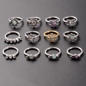 Flat lay of 12 stainless steel clicker rings featuring opal and zircon inlays