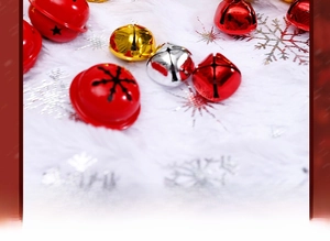 Close-up of red, gold, and silver metal Christmas bells on a white snowflake plush fabric