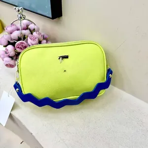 Detail of yellow pebbled leather crossbody bag with designer blue wavy shoulder strap