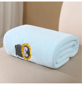 Close-up of soft light blue coral fleece baby blanket with cute penguin embroidery
