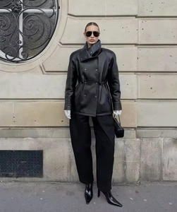 Detailed street style view of a black double-breasted PU leather jacket with high collar