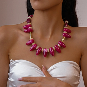 Macro detail of acrylic drop beads with gold tube accents on a stylish beaded necklace