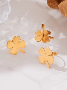 Detailed view of three golden clover rings with brushed texture on white marble background