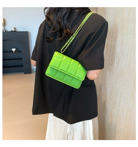 Detailed view of green quilted crossbody bag with gold chain strap worn by a model