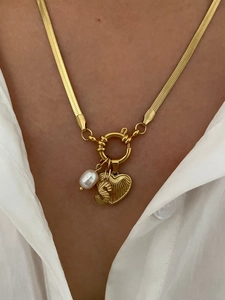 Close-up of gold snake chain necklace with pearl, letter S and heart pendant charms