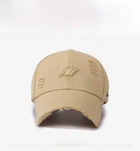 Detail of distressed beige cotton baseball cap featuring 3D wavy embroidery and frayed holes