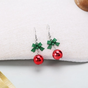 Festive Christmas earrings with green glitter bows and red metal beads on white fabric