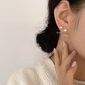 Detail of 925 sterling silver ball stud earrings in 6mm and 7mm sizes on a model