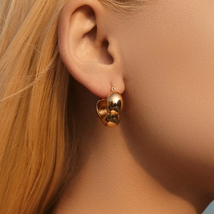 Macro shot of gold plated triple bead earrings showing high polish finish and fit