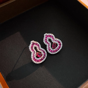 Détail macro de boucles d'oreilles gourde en argent avec pierres rouges et cristaux blancs