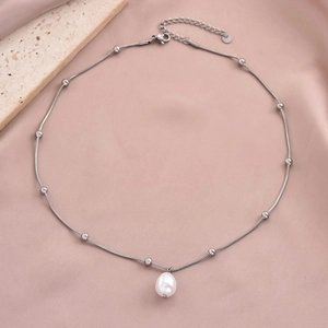 Detailed macro view of a silver bead chain with a natural pearl on pink silk