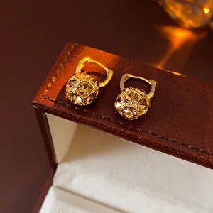 Gold plated ball hoop earrings with pavé crystal accents on a leather jewelry box