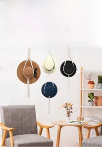 Detail of macramé cotton cord hat hanger holding colorful straw hats on wood rings