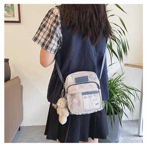 Détail du sac bandoulière en toile avec fenêtre transparente et breloque ourson
