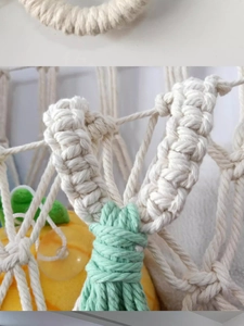 Macro shot of cotton rope weaving knots and green tassel detail on hanging mesh hammock