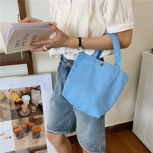 Sky blue canvas lunch bag with gold metal snap button shown in a casual lifestyle setting