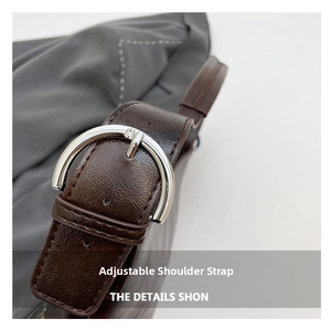 Detail of adjustable dark brown leather shoulder strap with silver buckle and fine stitching
